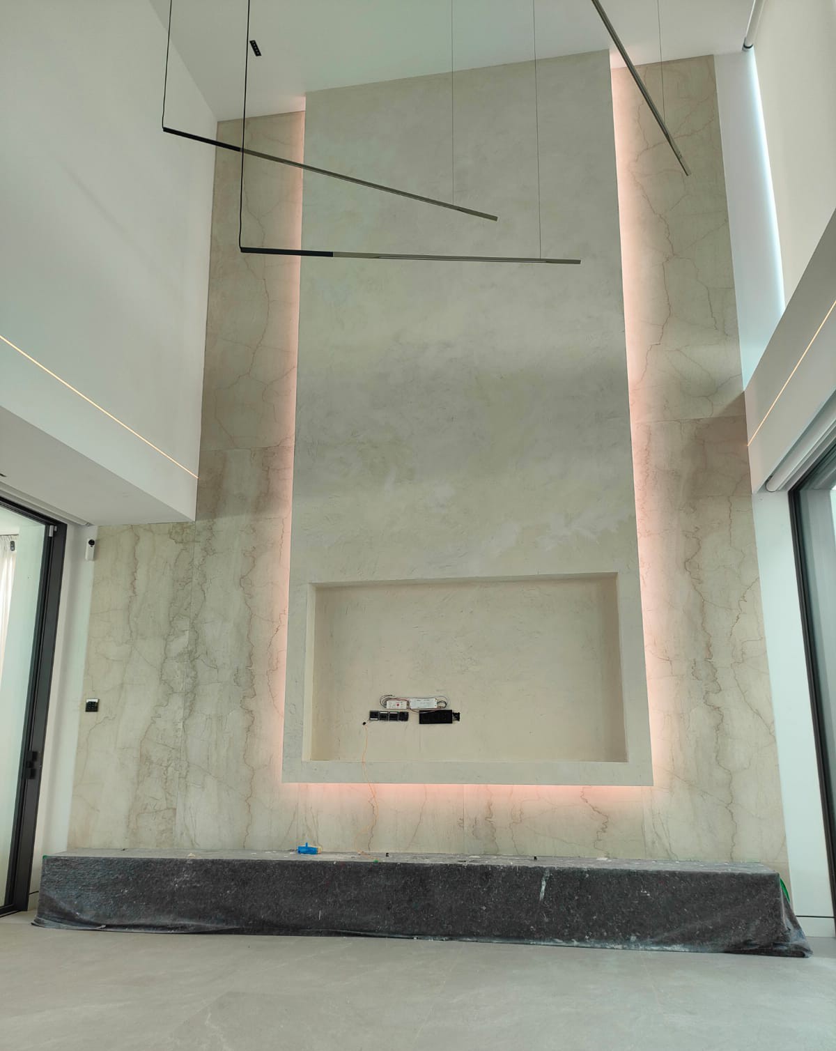 Centralna ściana TV ze spieków kwarcowych i mikrocementu z oświetleniem LED